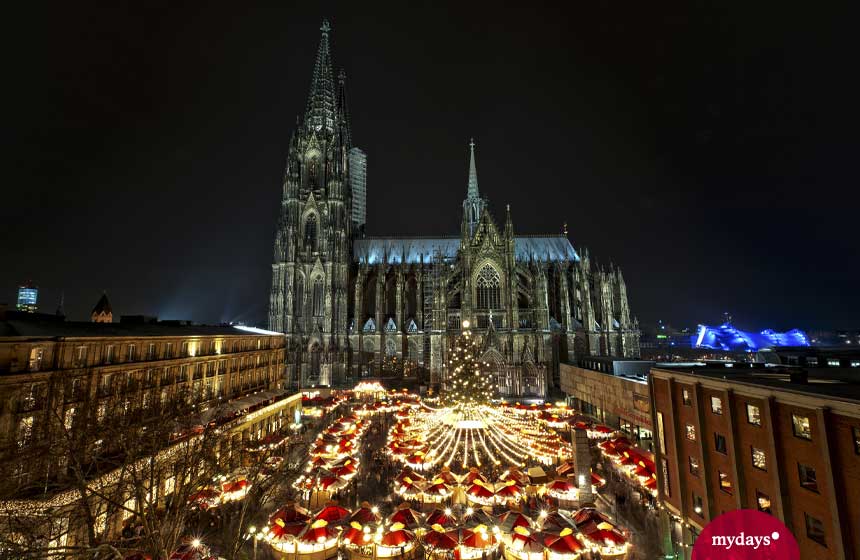 Der Kölner Dom mit dem beleuchteten Weihnachtsmarkt davor