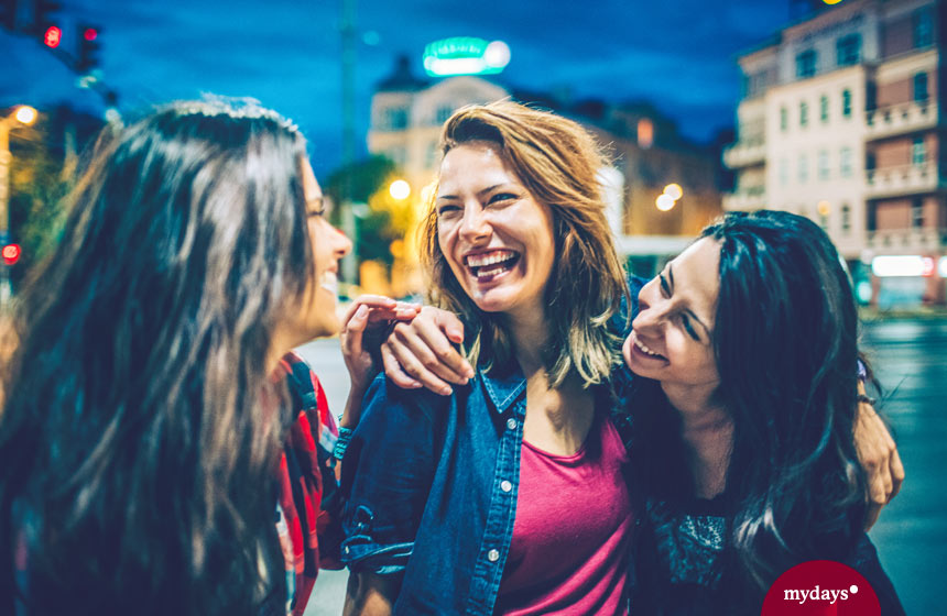 Drei Frauen lachen bei Nacht auf einer Straße