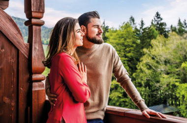 Frau mit rotem Pullover und Mann mit braunem Pullover auf Balkon