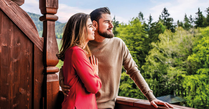 Frau mit rotem Pullover und Mann mit braunem Pullover auf Balkon