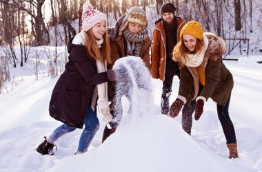 vier Freunde bauen einen Schneemann oder eine Schneebar